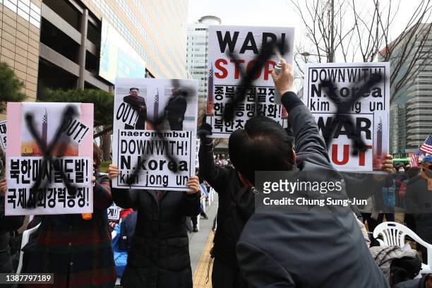 Protester spray paints "X marks" on placards during a rally against the North Korea's intercontinental ballistic missile launch on March 26, 2022 in...