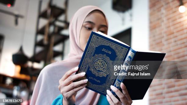 asian woman reading the quran - coran photos et images de collection