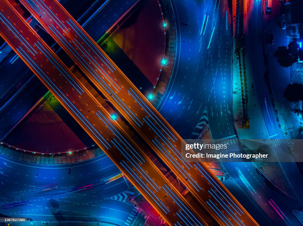 Aerial top view, Highway road roundabout intersection or circle at night for transportation that facilitates the travel of car users on the road transportation or futuristic concept.