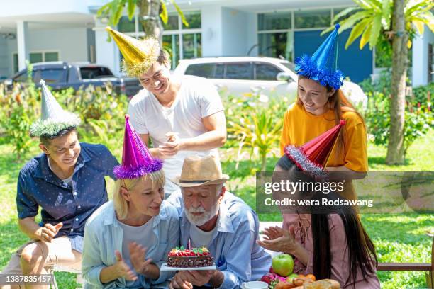 senior couple blowing birthday cake candle to celebrate with family - parents children blow candles asians foto e immagini stock