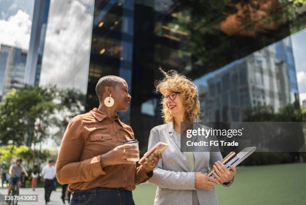 femmes d’affaires parlant en marchant à l’extérieur - alliances photos et images de collection