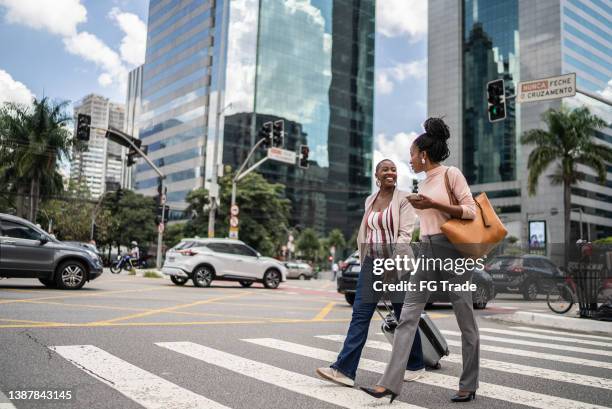 business women talking while walking outdoors - business woman suitcase stockfoto's en -beelden