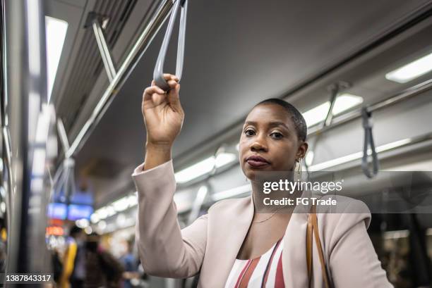 portrait d’une femme adulte tenant la poignée dans la rame de métro - femme métro photos et images de collection