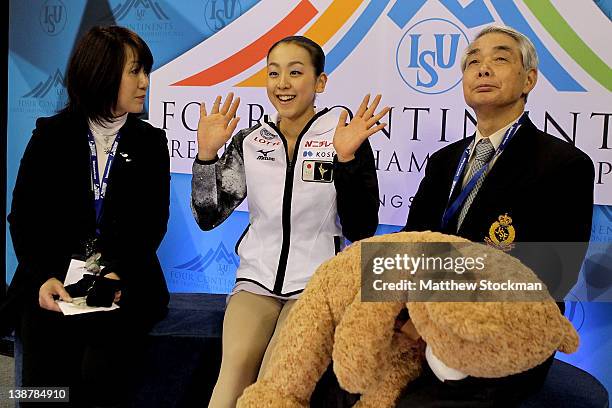 Reiko Kobayashi, Mao Asada of Japan and her coach, Nobuo Sato, watch her scores after the Ladies Free Skate during the ISU Four Continents Figure...