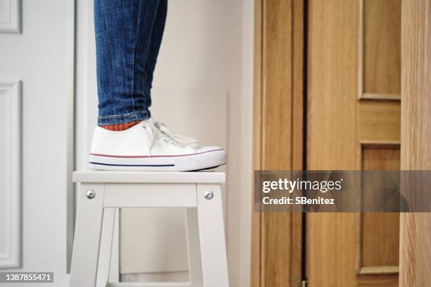 woman climbing a portable ladder inside a house - step stool stock pictures, royalty-free photos & images