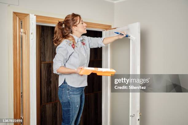 young woman painting a door - blocking door stock pictures, royalty-free photos & images