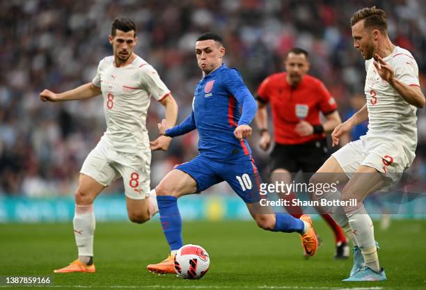 Phil Foden of England runs with the ball from Silvan Widmer of Switzerland during the International Friendly match between England and Switzerland at...