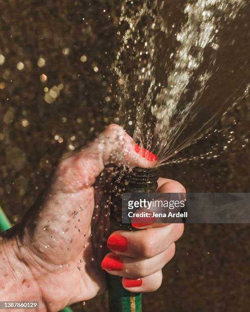 hand holding hose, running water outside, red nails, red nailpolish - squirting stock pictures, royalty-free photos & images