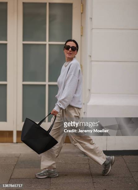 Elise Seitz is seen wearing New Balance grey sneaker, COS beige wide linen pants, Soho Studios grey oversized sweater, Nina Kastens gold bold chain,...