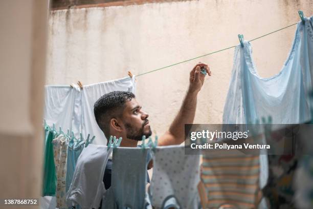 man hanging clothes on clothesline - wasknijper stockfoto's en -beelden