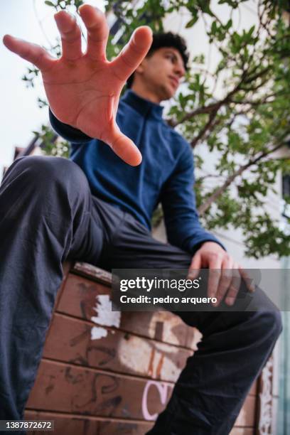 young man posing with his hand to catch something - catch 22 foto e immagini stock