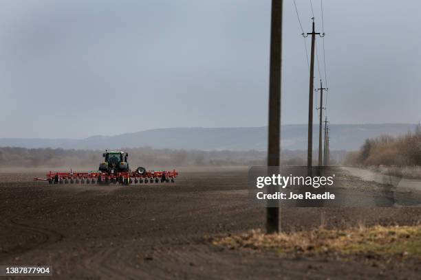 Farmer Morda Vasyl drives a tractor pulling a planter with sugar beet seeds on the Zahidnyi Bug Farm on March 26, 2022 in Humnyska, Ukraine. With...