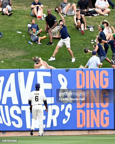 Fan catches a home run ball hit by Taylor Trammell of the Seattle Mariners as Lorenzo Cain of the Milwaukee Brewers looks on during the third inning...