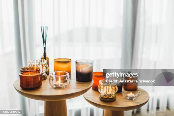 scented candles in different candlelights on wooden table at home. - velas imagens e fotografias de stock