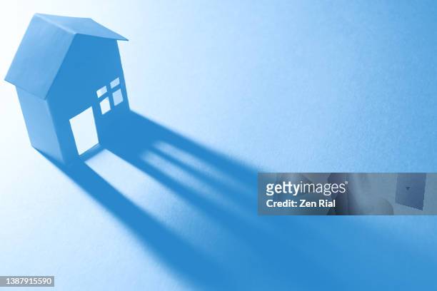 backlit paper house and long shadow and the colors converted to blue - housing difficulties bildbanksfoton och bilder