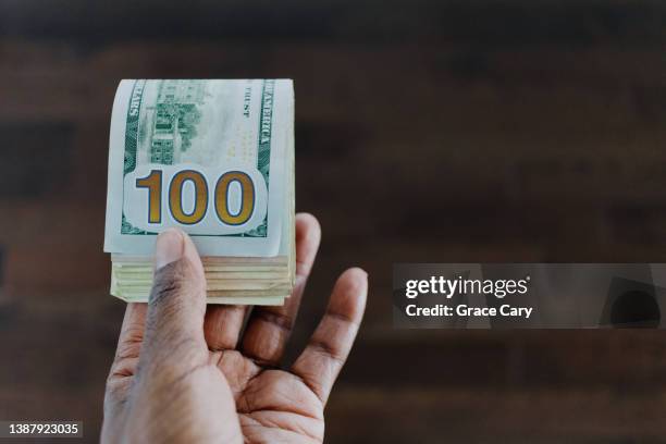 woman holds folded stack of us bills - compito a casa fotografías e imágenes de stock