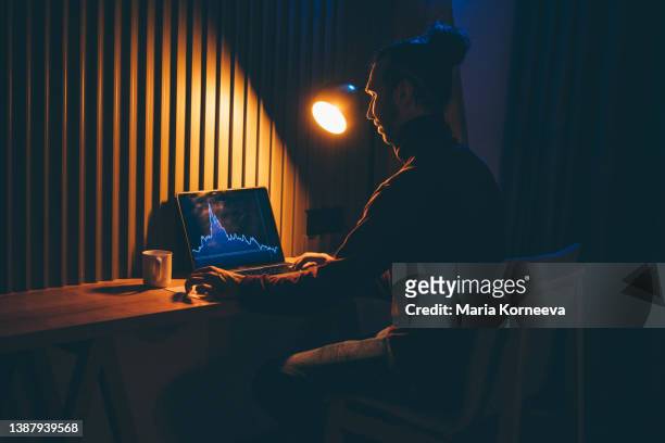 businessman looking at graph diagram on laptop at home during night. - recessed lighting fotografías e imágenes de stock