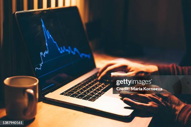 laptop screen with graph diagram at the night. man looking at graph diagram on laptop. - depresión económica fotografías e imágenes de stock
