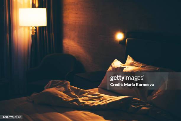 close-up of unmade bed at night. - empty dark bedroom stock pictures, royalty-free photos & images