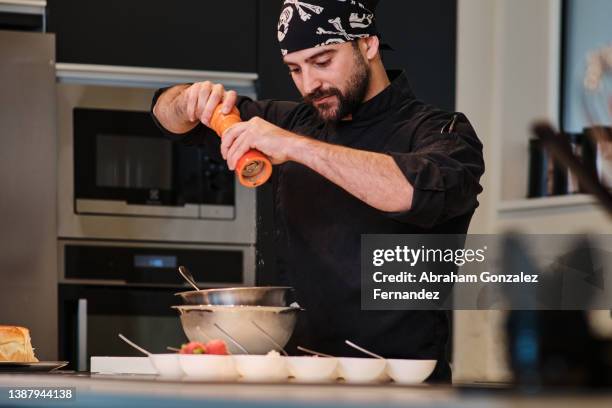 chef seasoning pepper on preparation in bowl in restaurant kitchen - pepper mill stockfoto's en -beelden