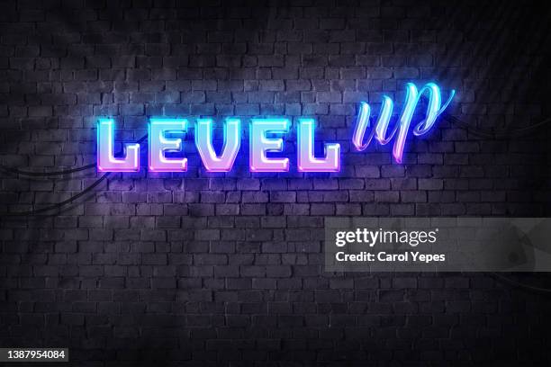 level up neon sign on brick wall background . - video game background stock-fotos und bilder