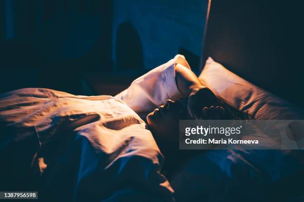 woman with insomnia. young woman lying on bed with hand on forehead. - waking up stock pictures, royalty-free photos & images