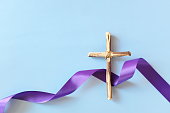 Top view flat lay of wooden cross crucifix with violet purple ribbon cloth with copy space. Holy week, lent season, Catholicism and Christianity concept.