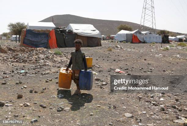 Yemeni internally displaced child, who fled home with his family escaping conflict, walks to collect water to his family's camp at a displaced...