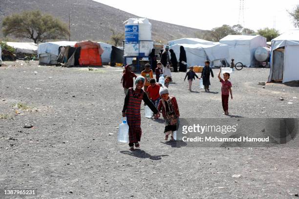 Yemeni internally displaced children, who fled homes escaping conflict, bring water to their shelters at a displaced persons camp on the outskirts of...