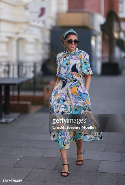 Anna Wolfers wearing a blue hair band, brown shades, a colorful and floral maxi dress and black heels via goldigshop.de on March 25, 2022 in Hamburg,...