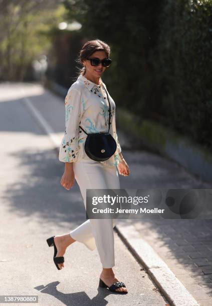 Anna Wolfers wearing brown shades, a beige blouse with floral pattern, a black leather bag, white jeans and black sandals via goldigshop.de on March...