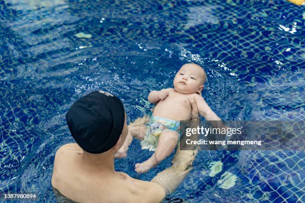 a young asian father swims with his baby. - babyschwimmen stock-fotos und bilder