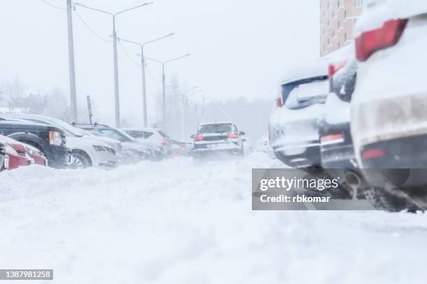 vehicles on street during snowfall - schneewehe stock-fotos und bilder