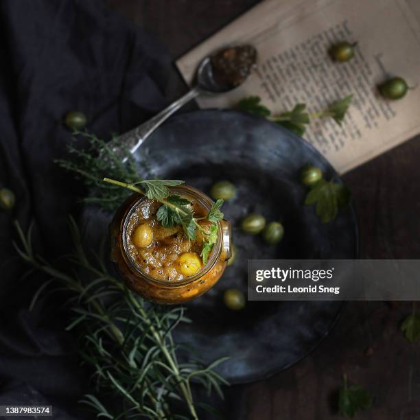 gooseberry jam or chutney in glass jar on dark background - uva spina foto e immagini stock