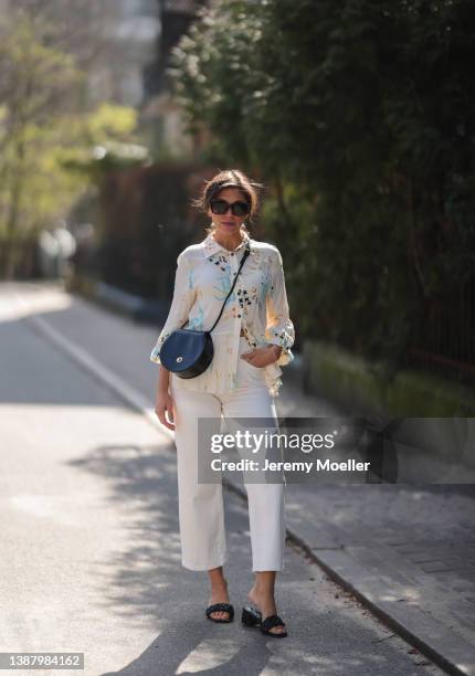 Anna Wolfers wearing brown shades, a beige blouse with floral pattern, a black leather bag, white jeans and black sandals via goldigshop.de on March...