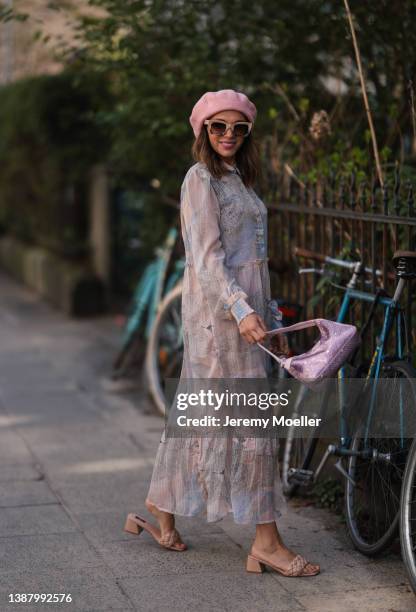 Anna Wolfers wearing a pink Prada Mini Hobo bag, a pink hat, beige and brown shades, a pink and grey maxi dress with pattern and beige sandals via...