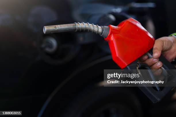 pumping equipment gas at gas station. close up of a hand holding fuel nozzle - pumps stock pictures, royalty-free photos & images
