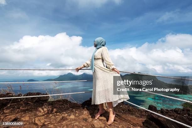 woman looking over scenic view of bohey dulang island - muslim woman beach stock pictures, royalty-free photos & images