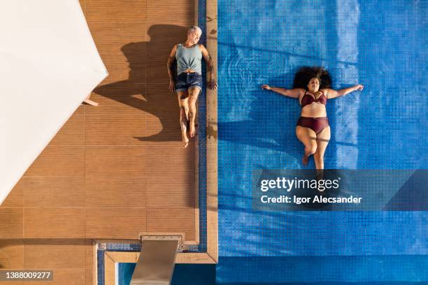 frauen verschiedener körper entspannen sich im pool - alte und junge lesbische frauen stock-fotos und bilder
