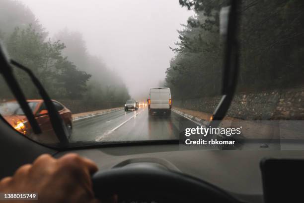 driving in hard weather conditions. car traffic along a forest highway during fog and rain - windschutzscheibe innen stock-fotos und bilder