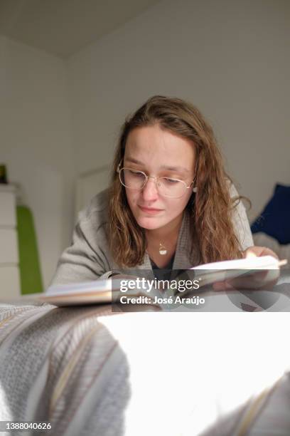 mujer disfrutando de su libro en la cama - descontrair fotografías e imágenes de stock