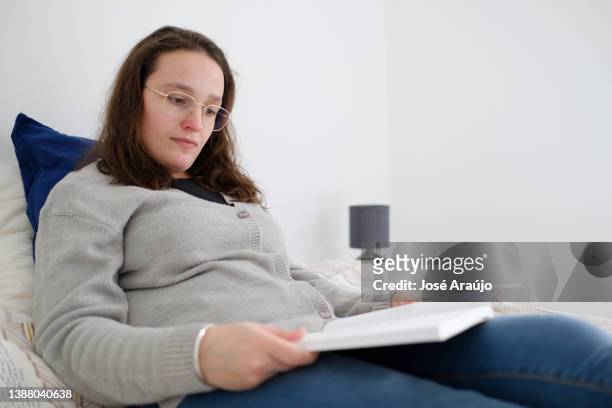 mujer disfrutando de su libro en la cama - descontrair fotografías e imágenes de stock