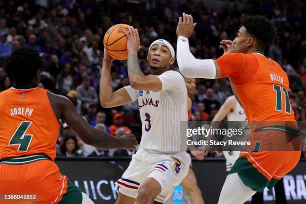 Dajuan Harris Jr. #3 of the Kansas Jayhawks drives to the basket against Bensley Joseph and Jordan Miller of the Miami Hurricanes during the second...