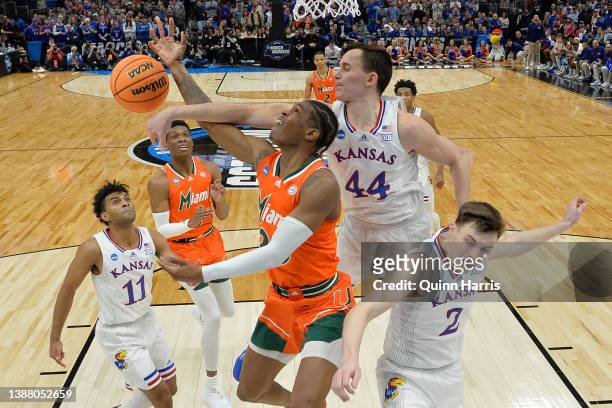 Kameron McGusty of the Miami Hurricanes drives to the basket against Mitch Lightfoot and Christian Braun of the Kansas Jayhawks during the second...
