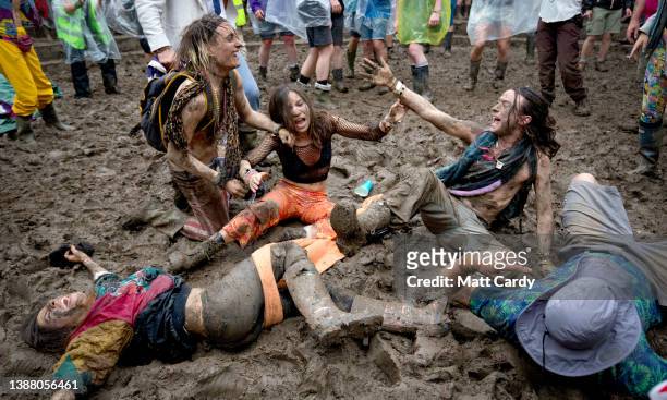 Festival revellers roll in the mud as they prepare to take part in a tomato fight during the 2016 Glastonbury Festival held at Worthy Farm, in Pilton...