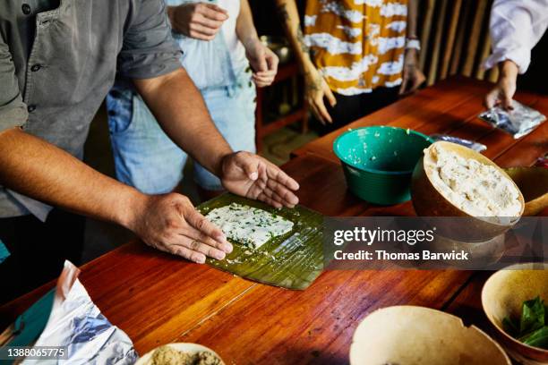 medium close up shot of chef helping woman fold tamale during mayan cooking class - tradicional fotografías e imágenes de stock