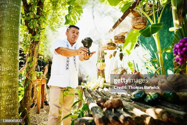 medium wide shot of man burning copal at altar for the mayan rain god chaak - eco tourism stock pictures, royalty-free photos & images