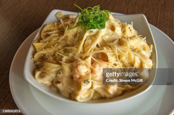 creamy shrimp tagliatelle pasta in a bowl on a plate - fettuccine alfredo stock pictures, royalty-free photos & images