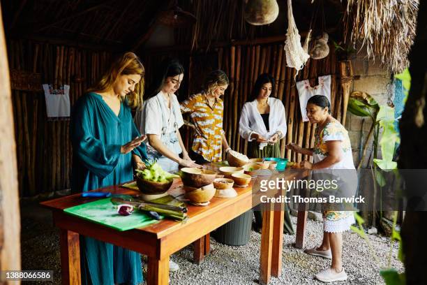 wide shot of group of friends taking traditional mayan cooking class while on vacation - cooking school stock pictures, royalty-free photos & images