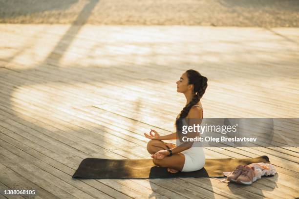 young woman meditating in lotus position. mental health and self care. morning ritual, calm and spiritual - healing prayer images stock pictures, royalty-free photos & images